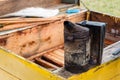 BeekeeperÃ¢â¬Ës tool making smoke on the opened yellow beehive